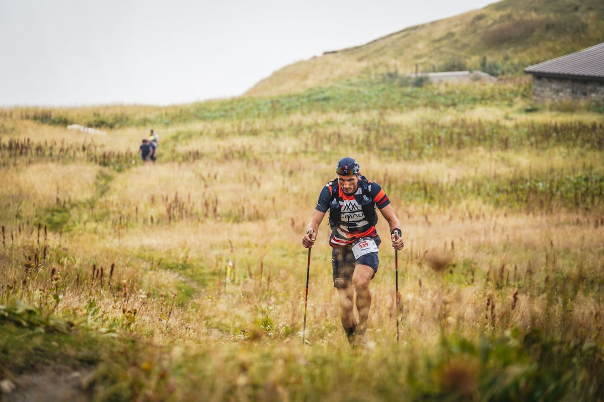 Coureur de l'UTMB traversant une prairie dorée de montagne
