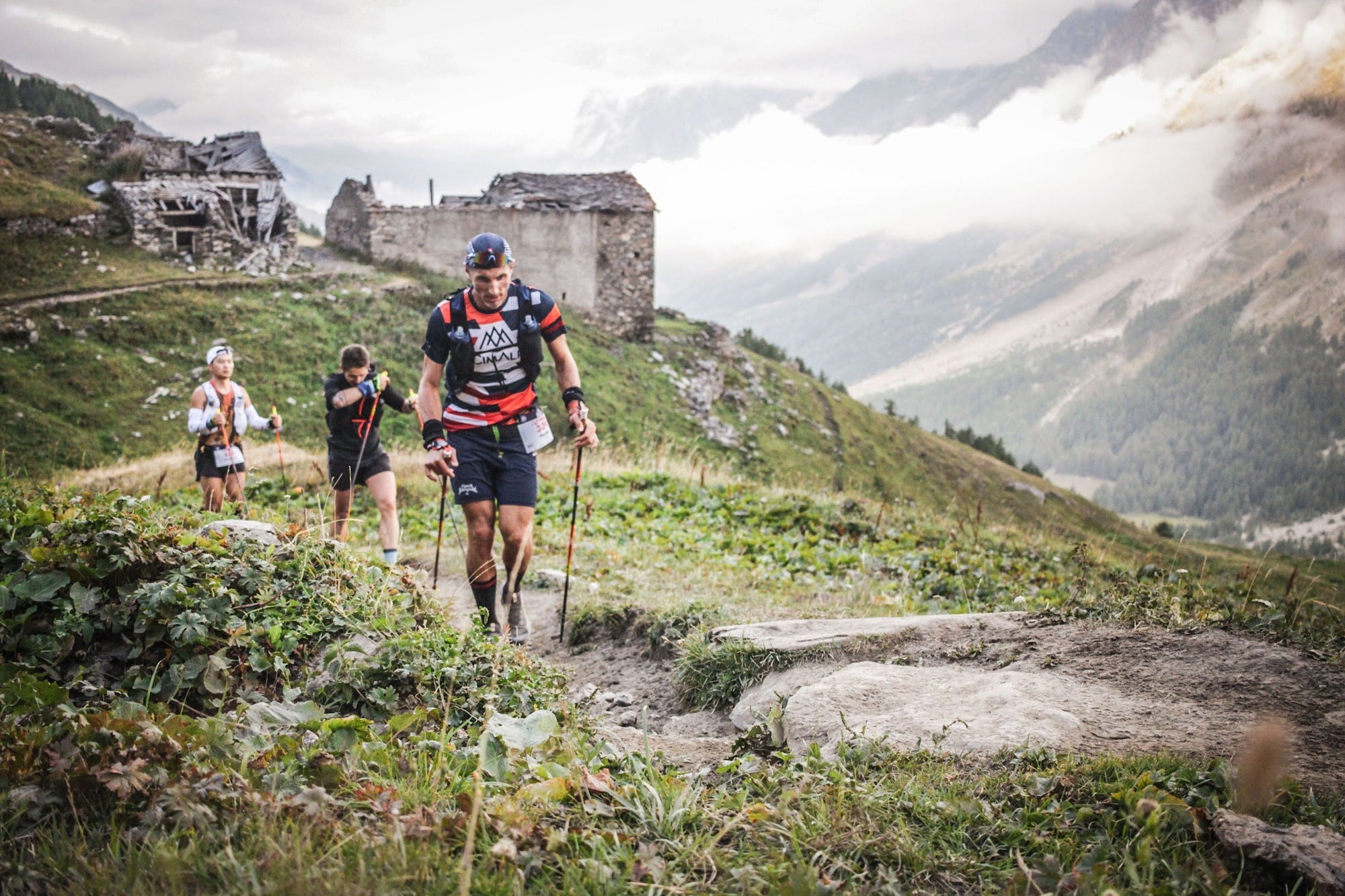 Coureurs d'ultra-trail passant devant un refuge de montagne