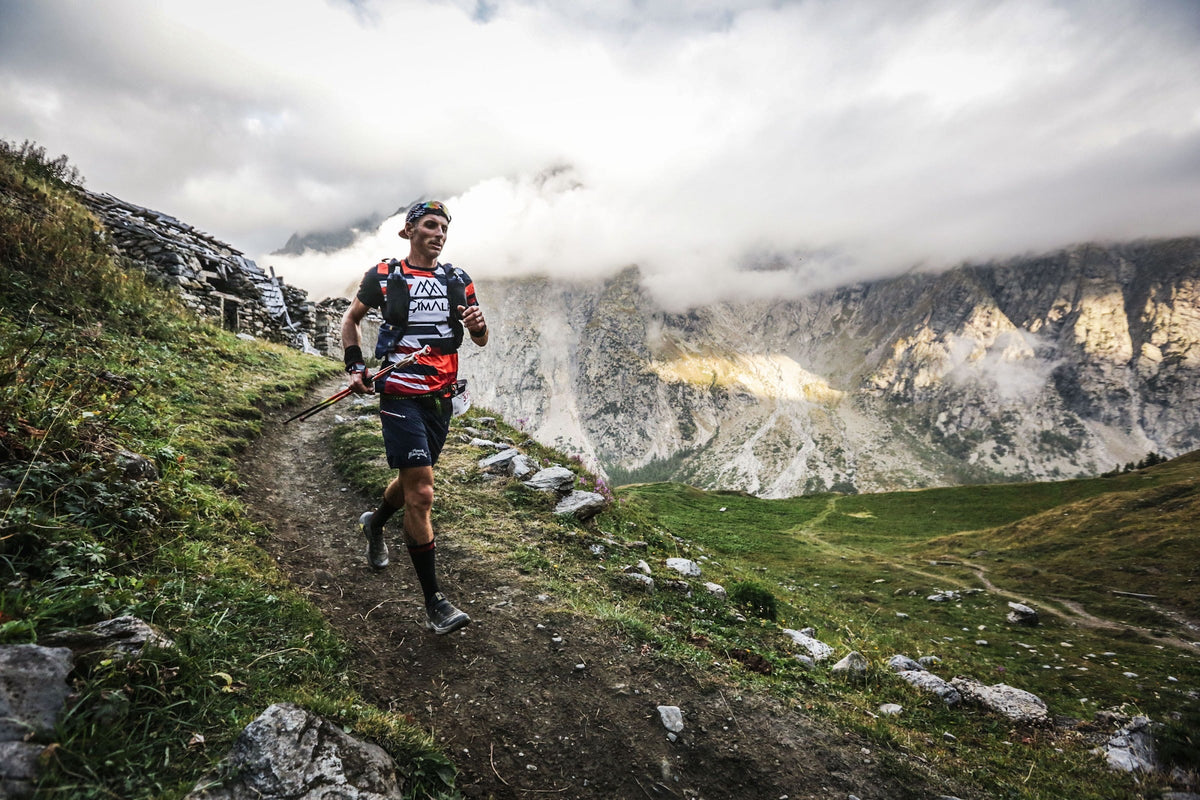 Coureur de l'UTMB sur un sentier en balcon au-dessus de la vallée