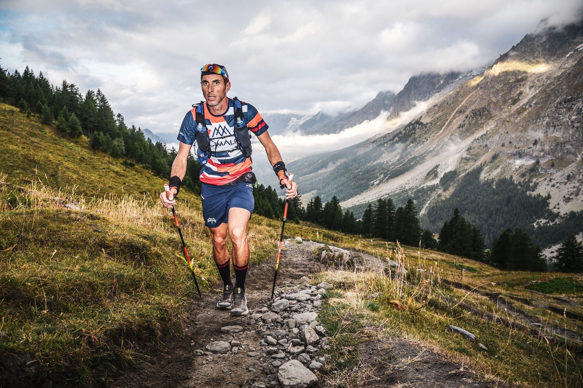 Coureur de l'UTMB sur un sentier d'alpage en montagne
