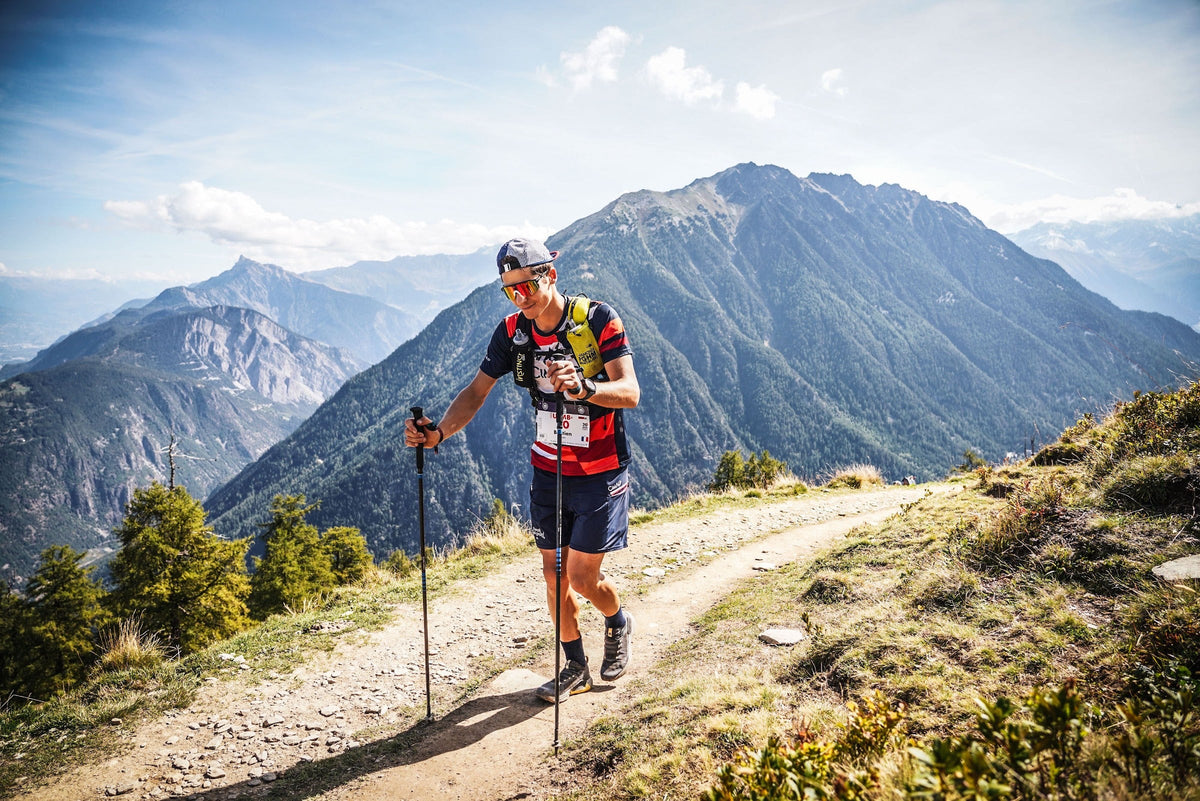 Coureur Cimalp avec bâtons face aux montagnes sur l'UTMB