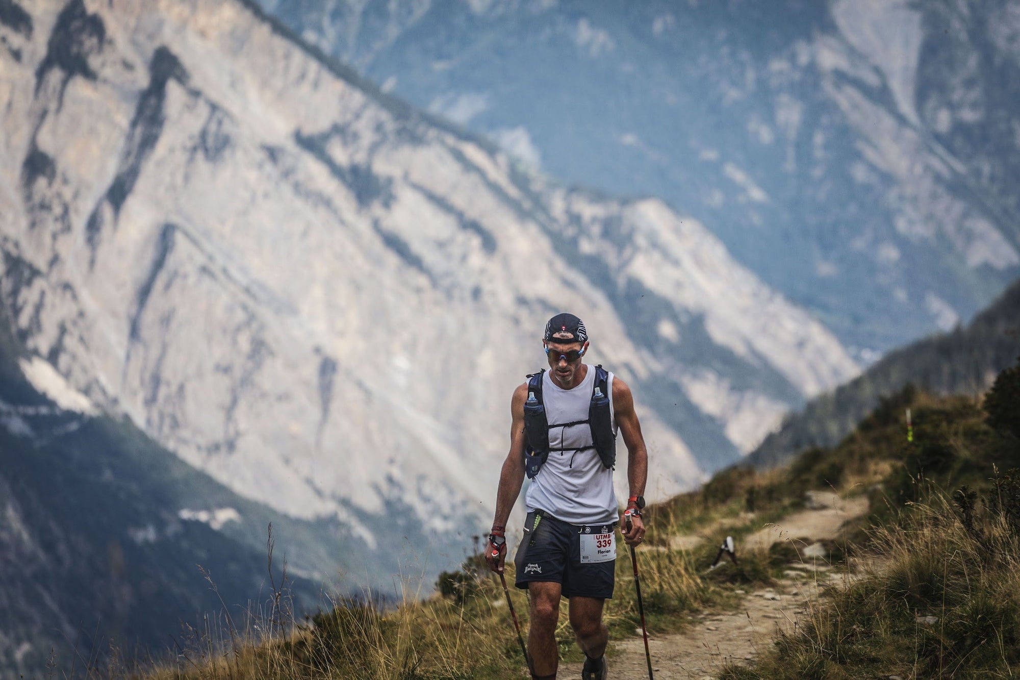 Coureur de l'UTMB sur un sentier exposé au pied d'une paroi rocheuse