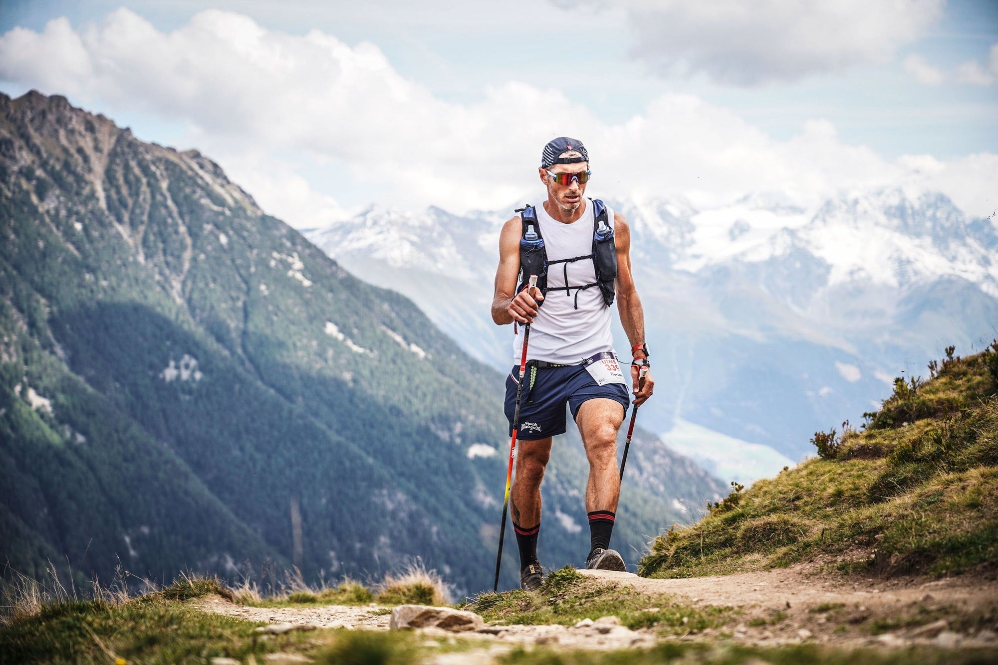 Coureur de l'UTMB face aux sommets enneigés du massif du Mont-Blanc